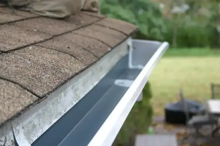 Gutter replacement installation on residential roof in St. James, NY by Home Team Construction.