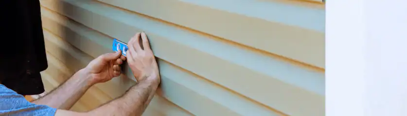 Expert vinyl siding repair service on house exterior by Home Team Construction.