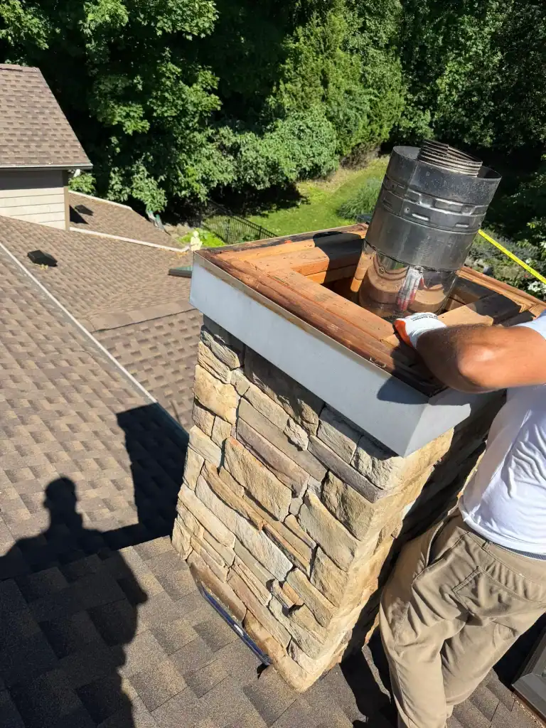 Chimney cleaning or inspection on a residential roof with a professional worker.