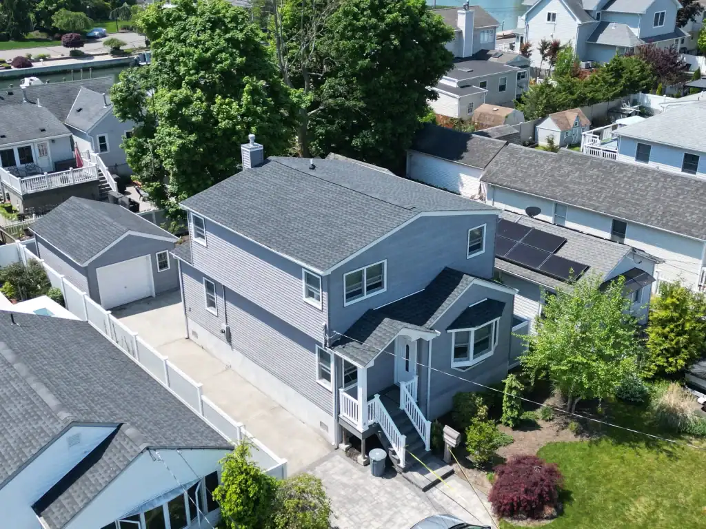 Modern two-story house with gray siding and white trim in a residential neighborhood.