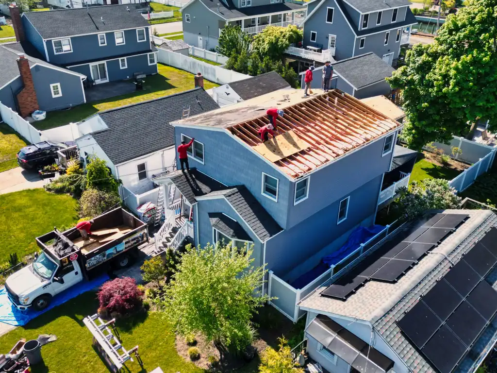 Home construction site with workers on roof in a residential neighborhood.