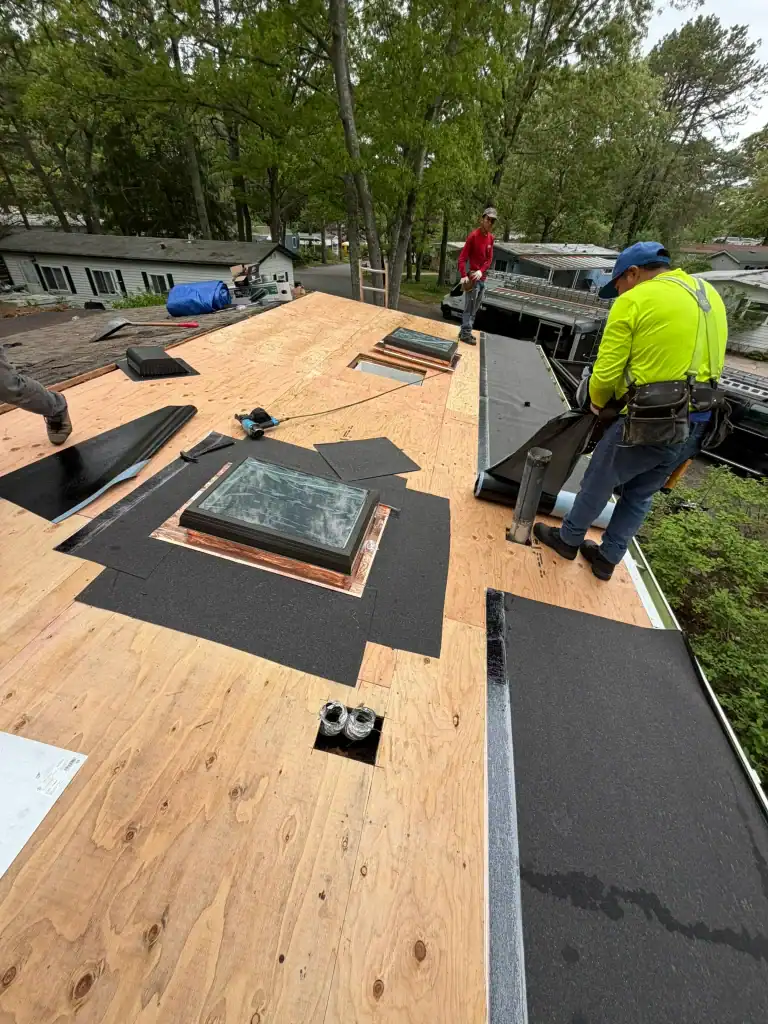 Two Home Team Construction workers laying shingles on a rooftop.