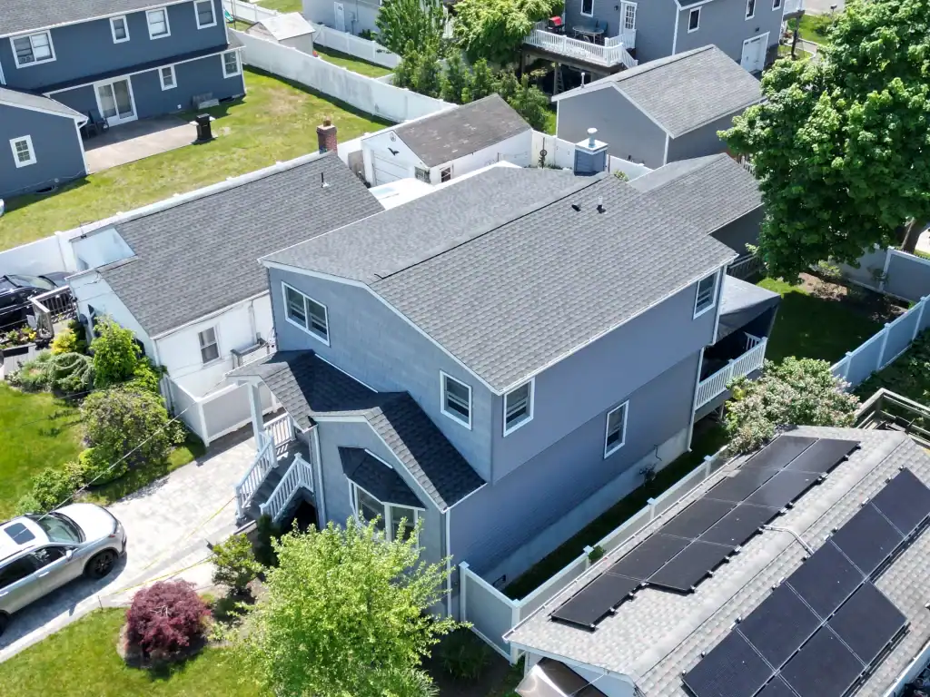 Aerial view of a modern residential house with solar panels and backyard.