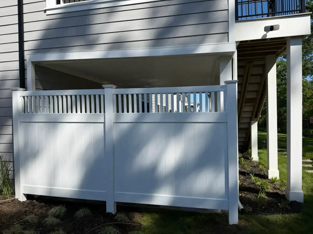 White privacy fence installed under a house with stairs leading up to the entrance.